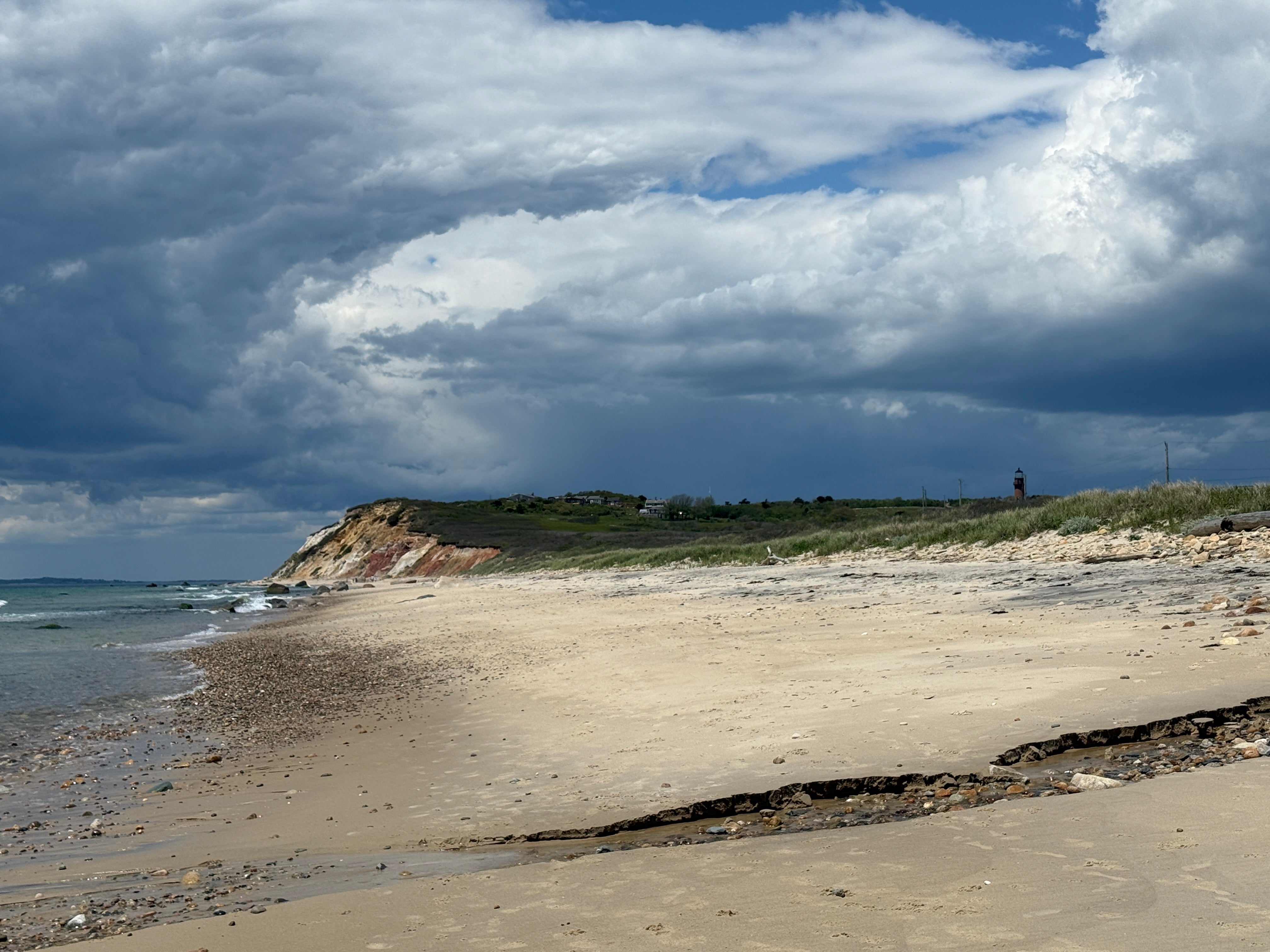 Beach scene with a grassy hill and cloudy sky