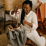 Woman sitting on the floor with a bag and a chair in the background