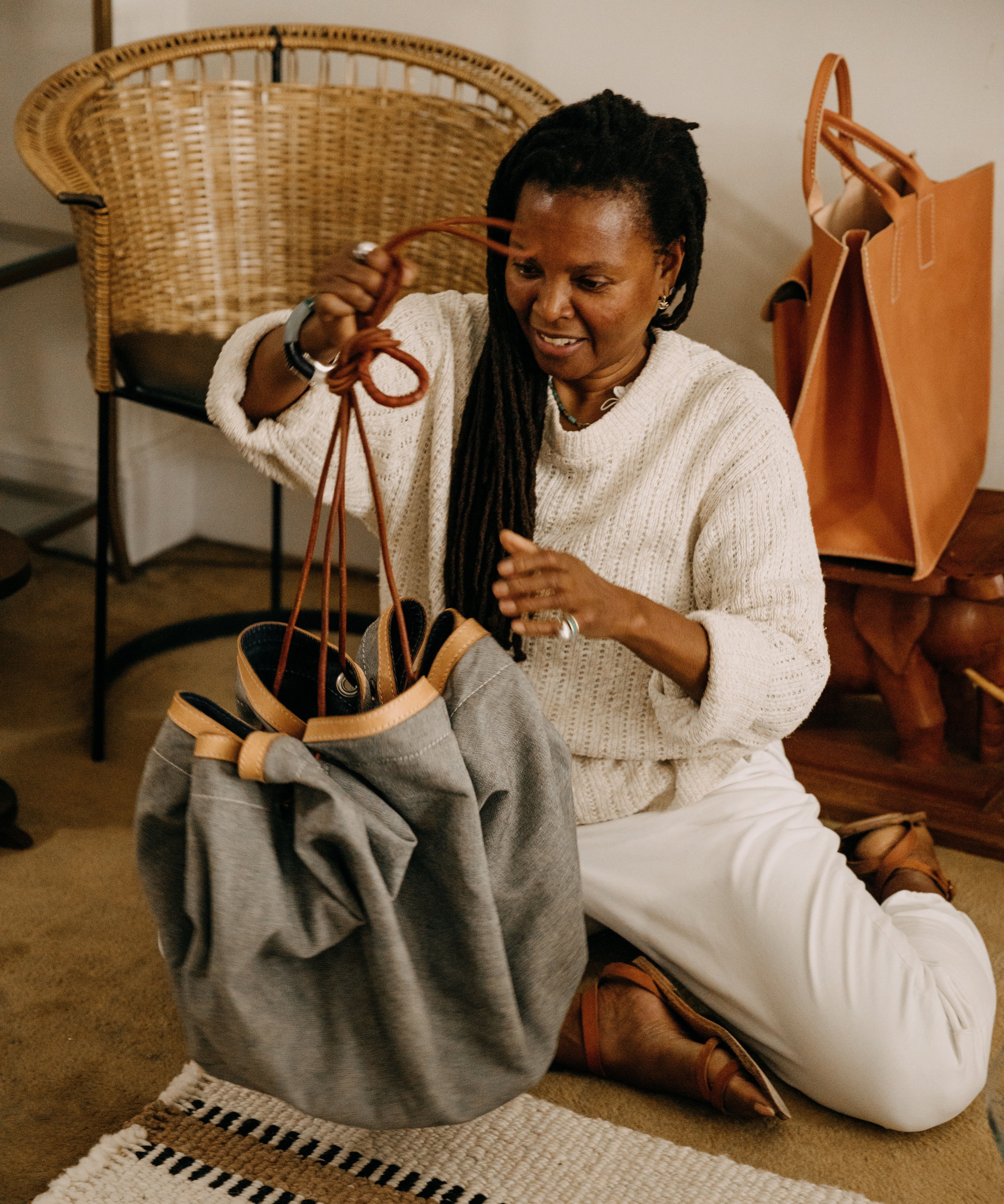 Woman sitting on the floor with a bag and a chair in the background