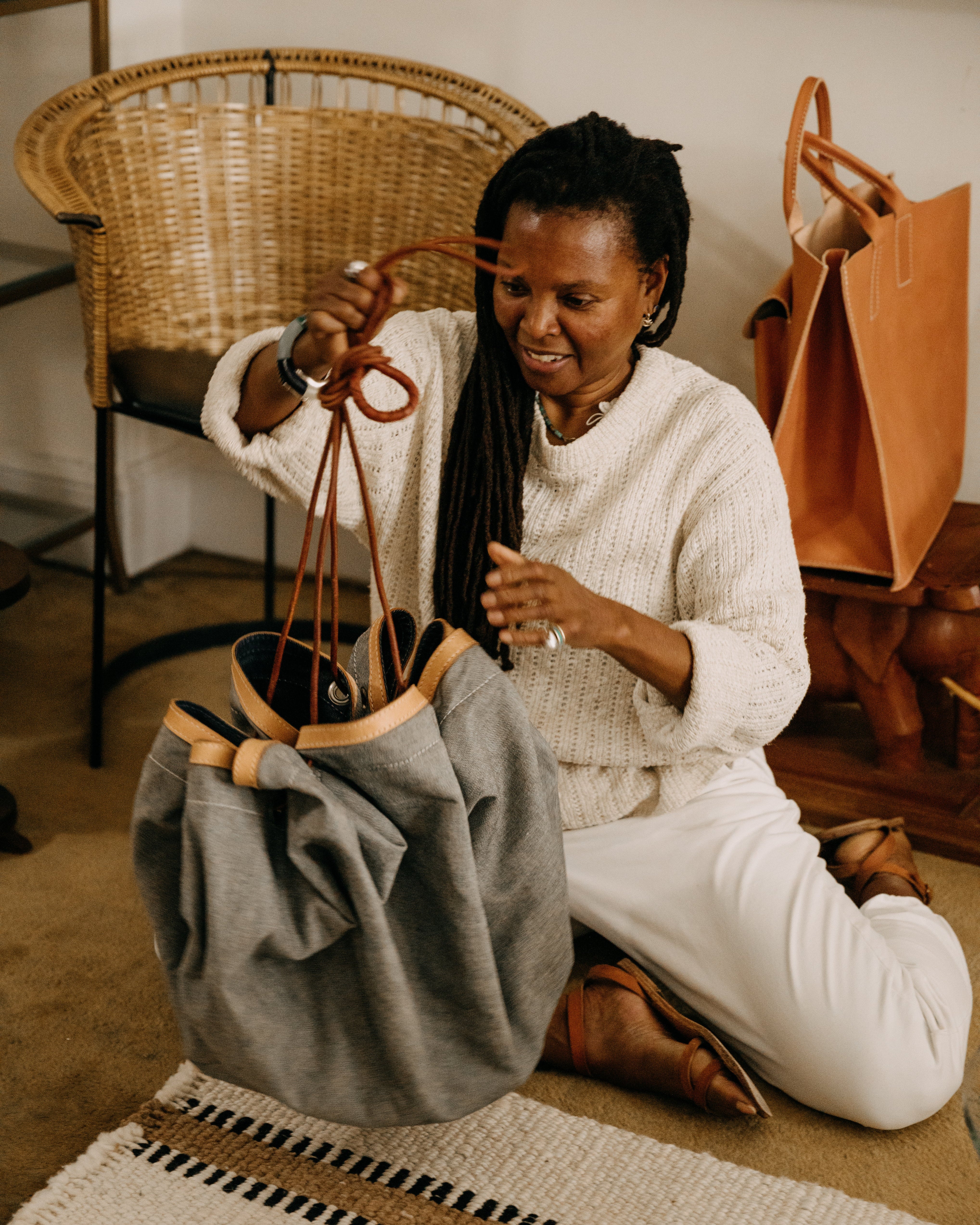 Woman sitting on the floor with a bag and a chair in the background