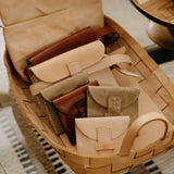 Basket with leather wallets on a woven surface