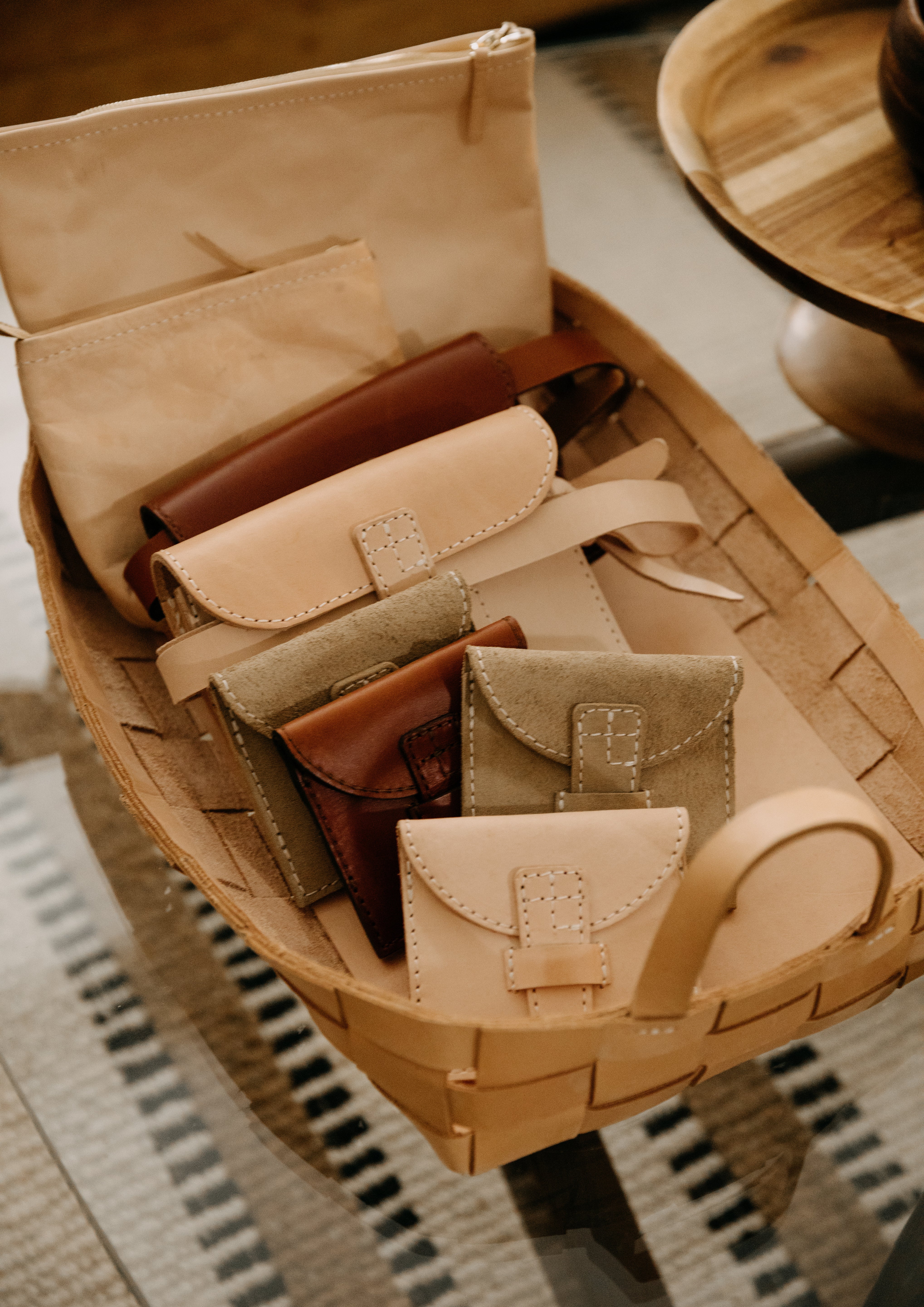 Basket with leather wallets on a woven surface