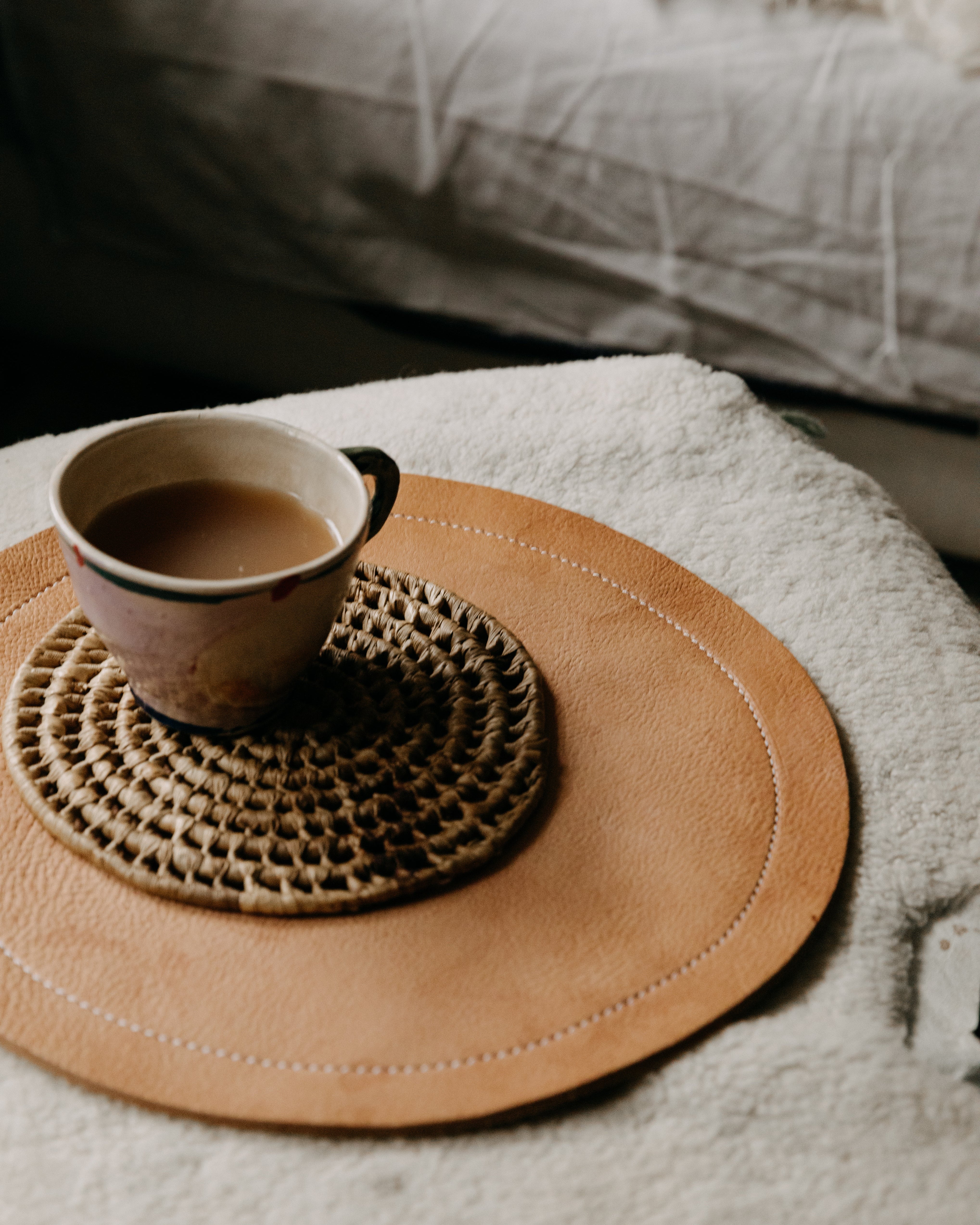 Cup of coffee on a woven coaster with a beige mat on a textured surface