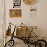 Vintage-style tricycle with bags against a wall with framed pictures