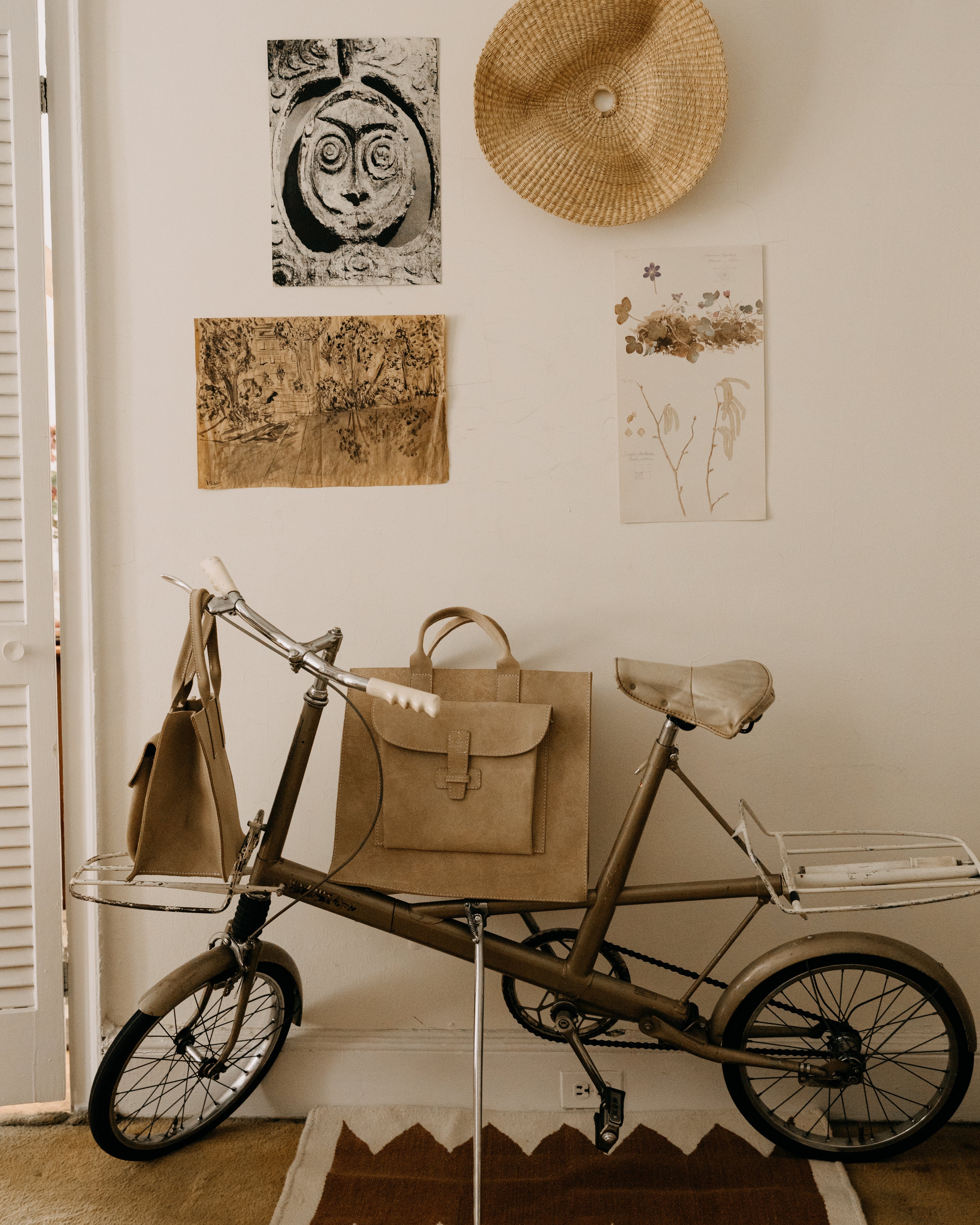 Vintage-style tricycle with bags against a wall with framed pictures