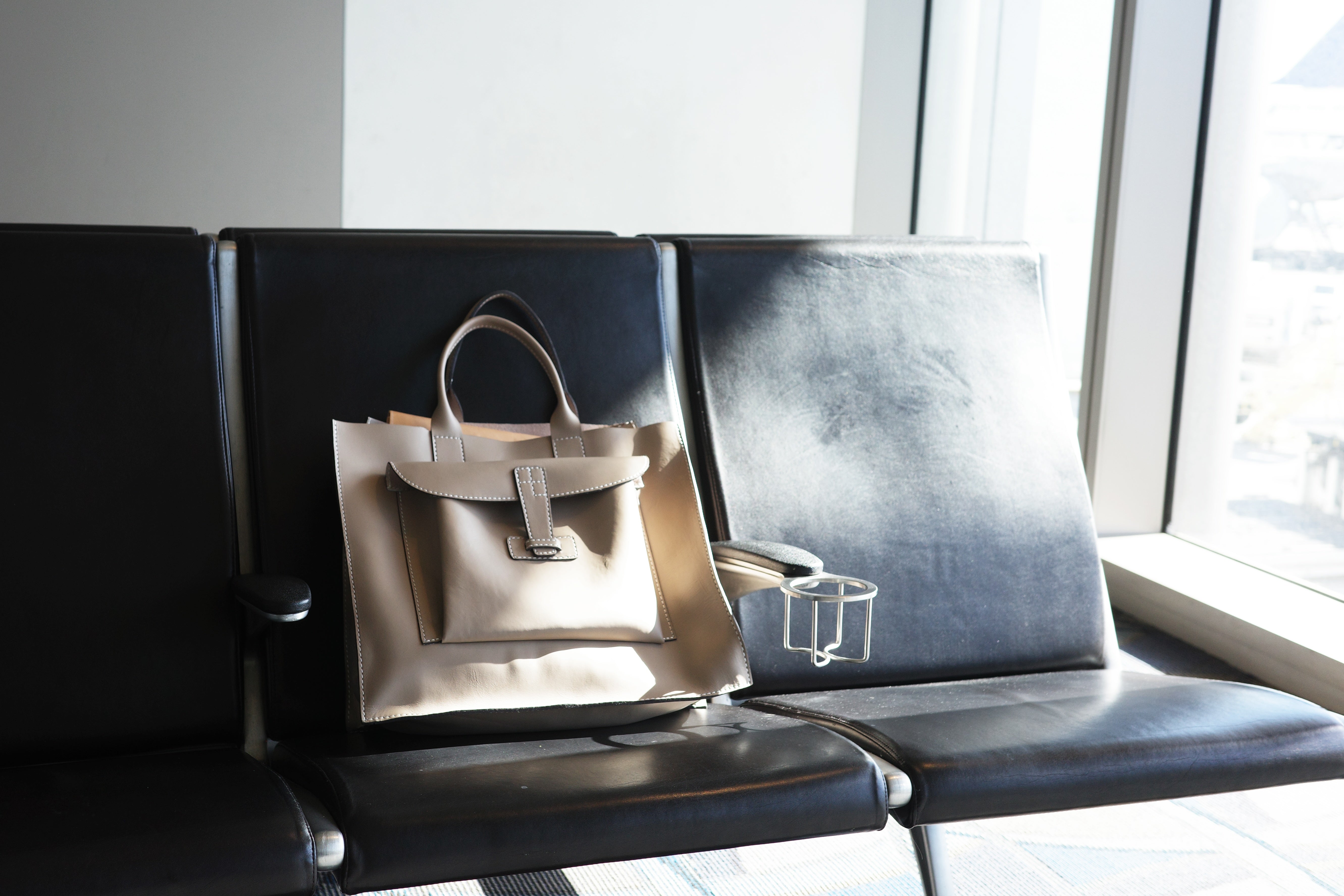 Taupe leather bag resting on airport seats. 